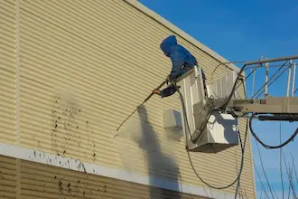 Man cleaning vinyl siding with power washer