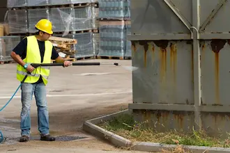Man cleaning sides of industrial building