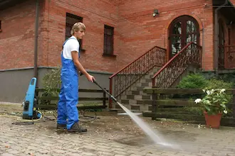 Man cleaning patio with high pressure cleaner